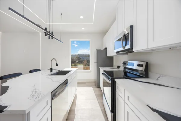 a kitchen with stainless steel appliances granite countertop a sink a stove and a refrigerator