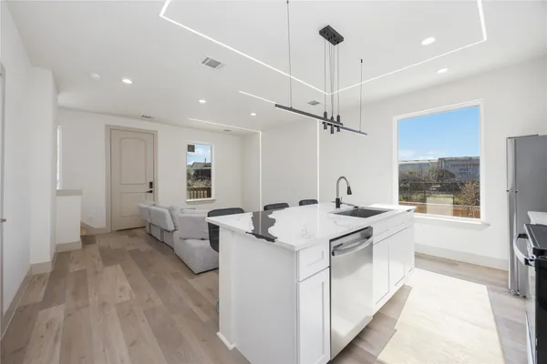 a open kitchen with stainless steel appliances granite countertop a sink and dishwasher with white cabinets