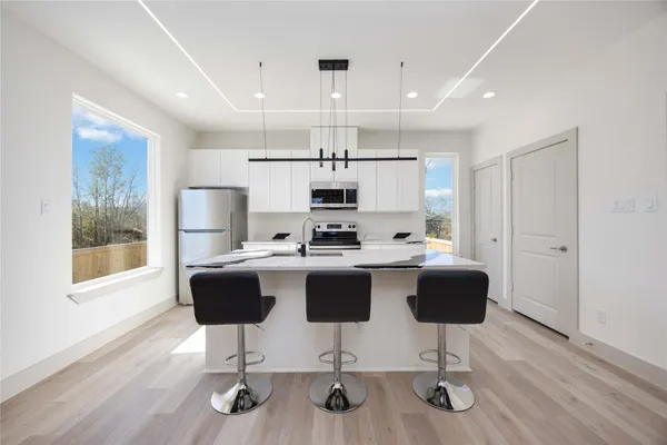 a view of kitchen with microwave stove refrigerator dining table and chairs