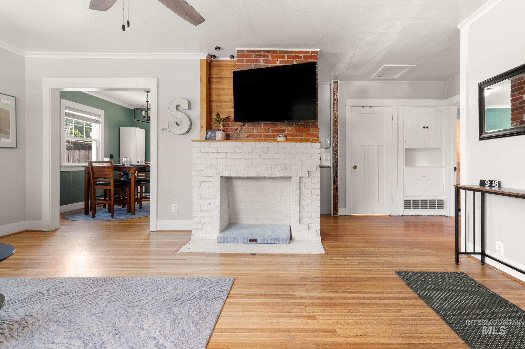 907 3rd Street Lewiston, ID 83501 - Photo 7 of 26 Living room with ornamental molding, light wood finished floors, a brick fireplace, and a ceiling fan