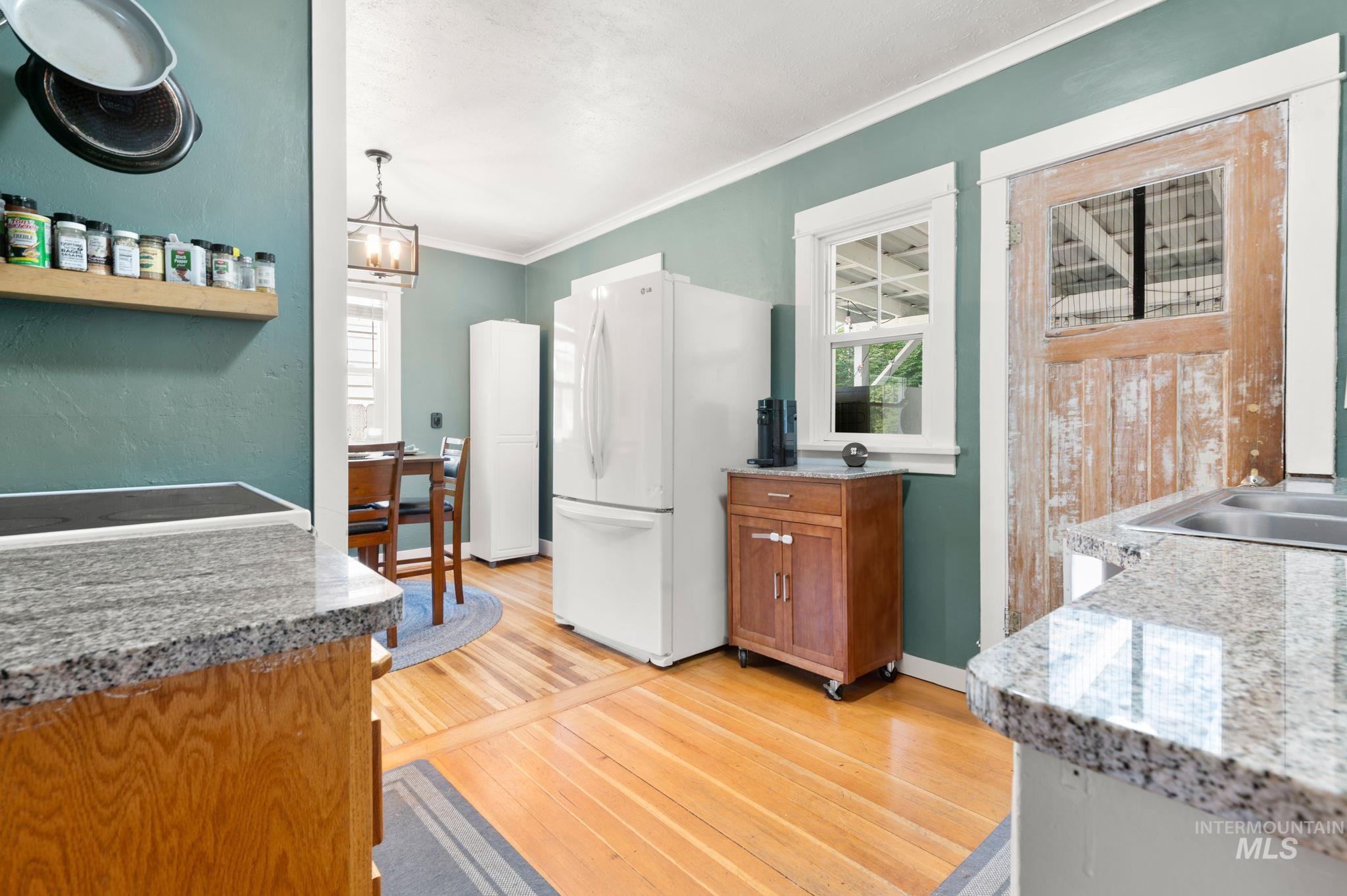 907 3rd Street Lewiston, ID 83501 - Photo 8 of 26 Kitchen featuring ornamental molding, freestanding refrigerator, plenty of natural light, wood finish cabinetry, and light stone countertops