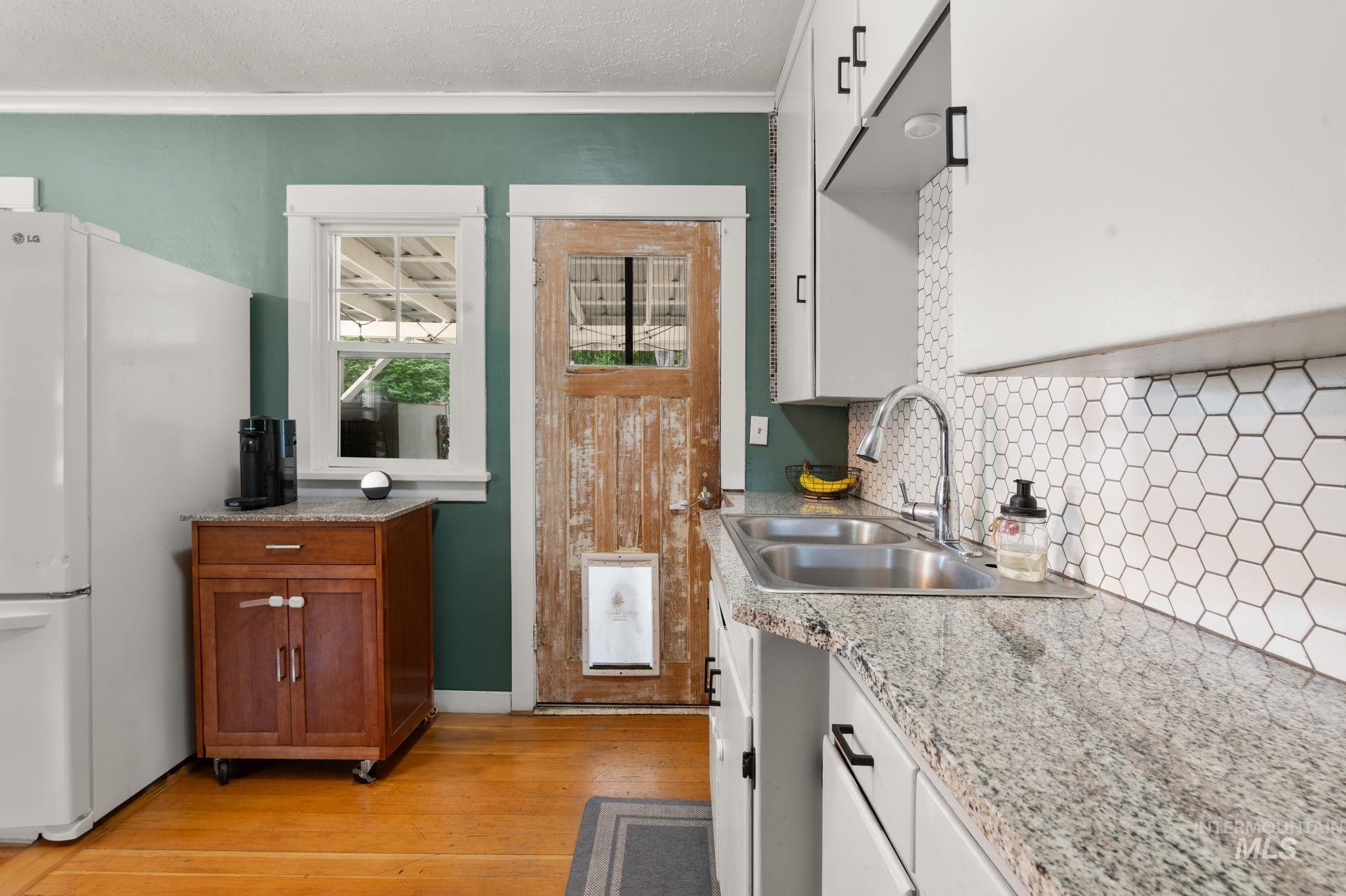 907 3rd Street Lewiston, ID 83501 - Photo 9 of 26 Kitchen featuring freestanding refrigerator, backsplash, a textured ceiling, light wood-style floors, and crown molding