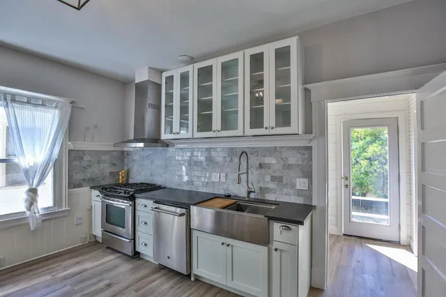 a kitchen with stainless steel appliances granite countertop white cabinets and window