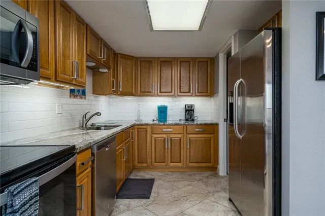 a kitchen with granite countertop stainless steel appliances granite countertop wooden cabinets a sink and dishwasher