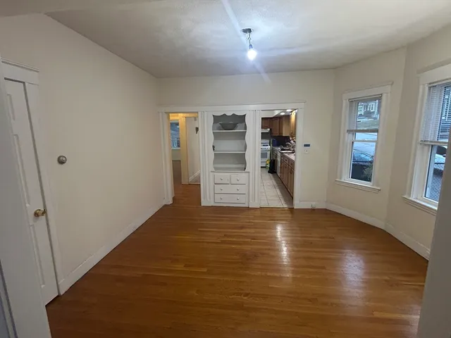 a view of empty room with wooden floor and window