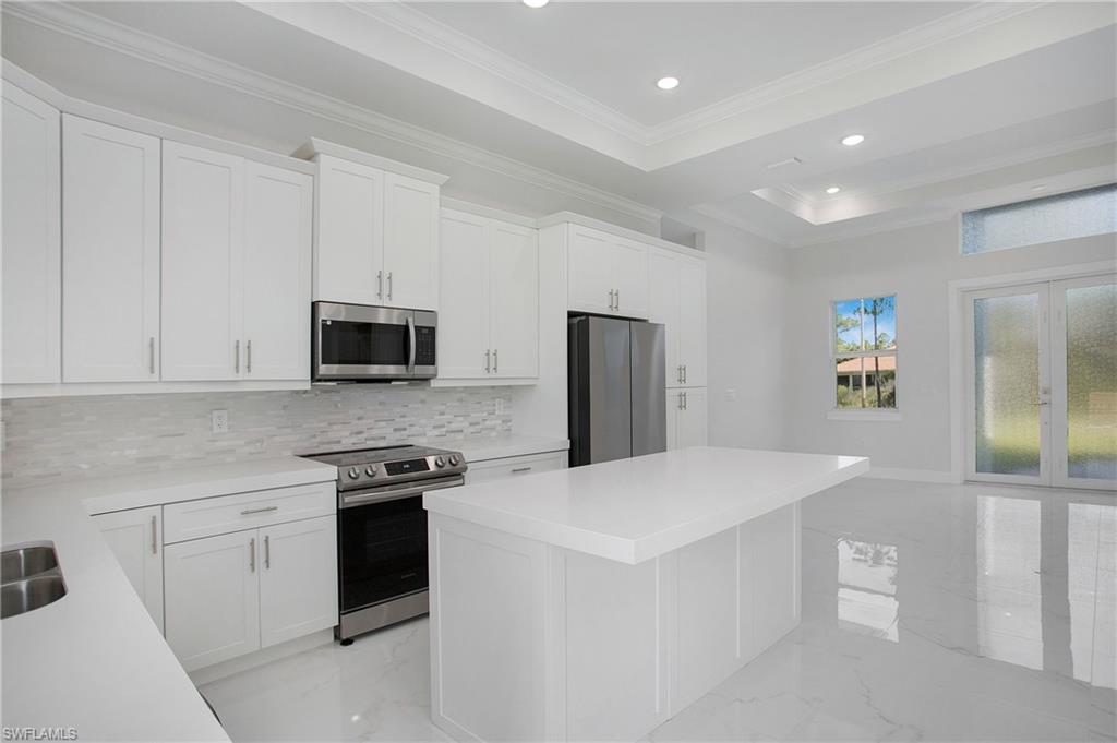2811 14th Street West Lehigh Acres, FL 33971 - Photo 9 of 33 a kitchen with stainless steel appliances a white refrigerator oven a sink dishwasher and white cabinets next to a window