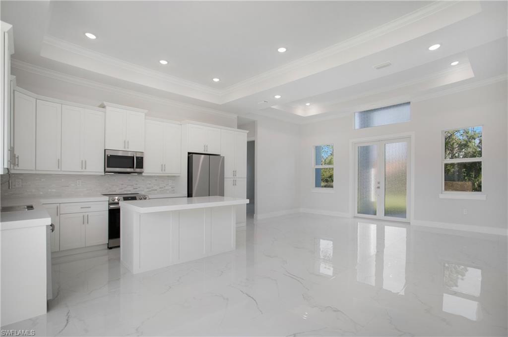 2811 14th Street West Lehigh Acres, FL 33971 - Photo 10 of 33 a large white kitchen with stainless steel appliances a stove a refrigerator a sink a microwave a stove and white cabinets