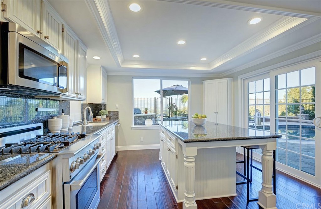 22805 Rio Lobos Road Diamond Bar, CA 91765 - Photo 15 of 50 a kitchen with stainless steel appliances a stove a sink dishwasher a microwave oven and a dining table with wooden floor