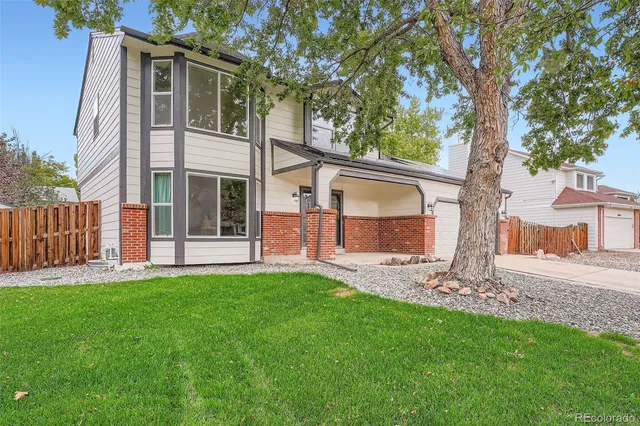 a view of a house with a yard and a large tree