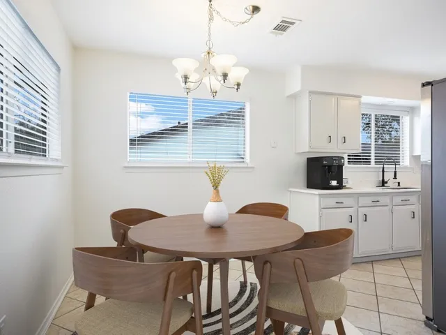 a kitchen with stainless steel appliances granite countertop a dining table chairs and a refrigerator