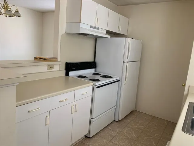 a kitchen with appliances a refrigerator and cabinets