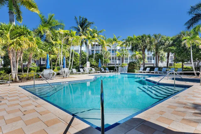 a swimming pool with outdoor seating and covered with trees
