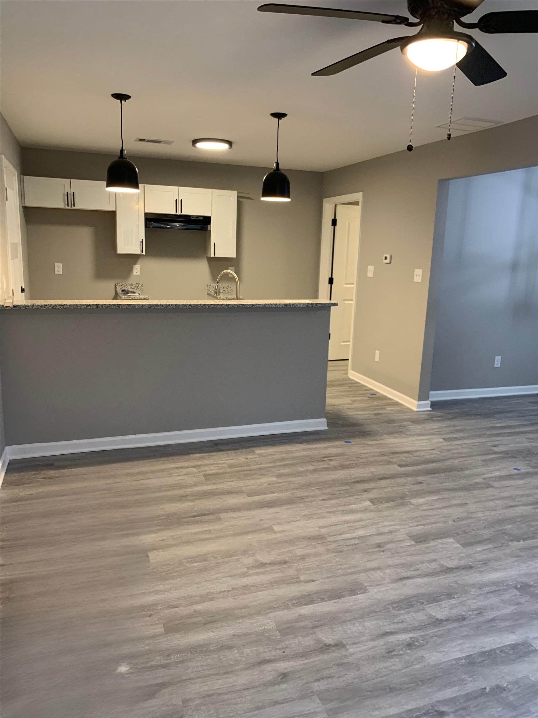 4372 Ryan Street Memphis, TN 38127 - Photo 9 of 9 Kitchen featuring white cabinets, hanging light fixtures, under cabinet range hood, and dark wood-type flooring