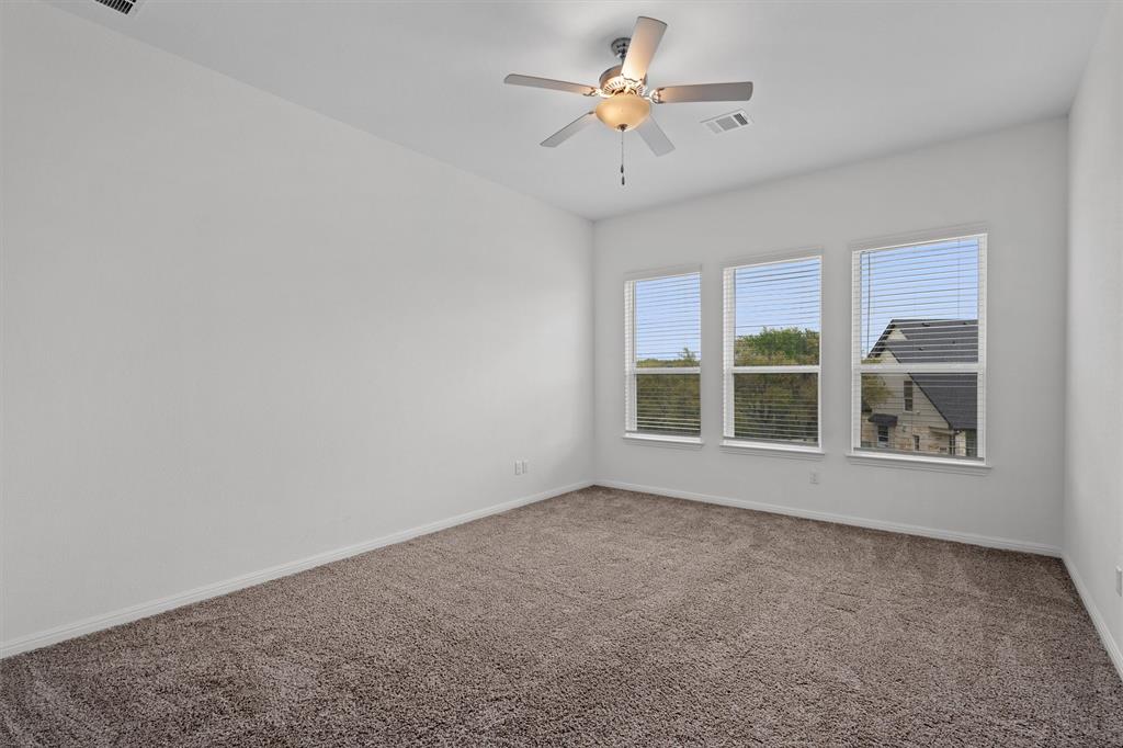 236 Prato Place Georgetown, TX 78628 - Photo 18 of 40 A quiet bedroom featuring plush carpeting and a ceiling fan, illuminated by a trio of windows with blinds.