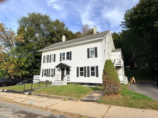 a view of a white house with a yard and plants