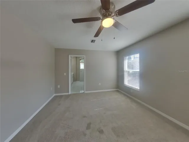 an empty room with windows and fan