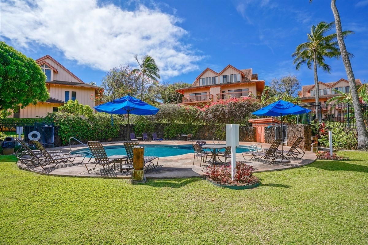 2370 Ho'ohu Road, Unit 522 Koloa, HI 96756 - Photo 1 of 29 a view of a house with garden and a table and chairs under an umbrella