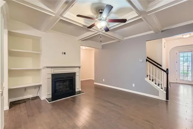 a view of an empty room with a fireplace and a ceiling fan
