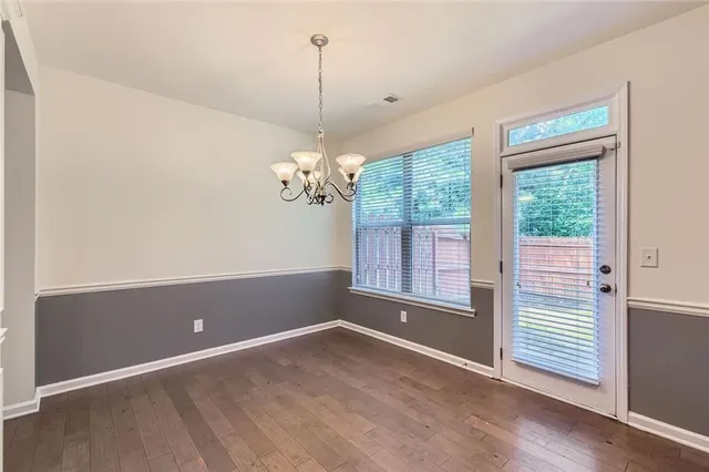 a view of a livingroom with a chandelier wooden floor and windows