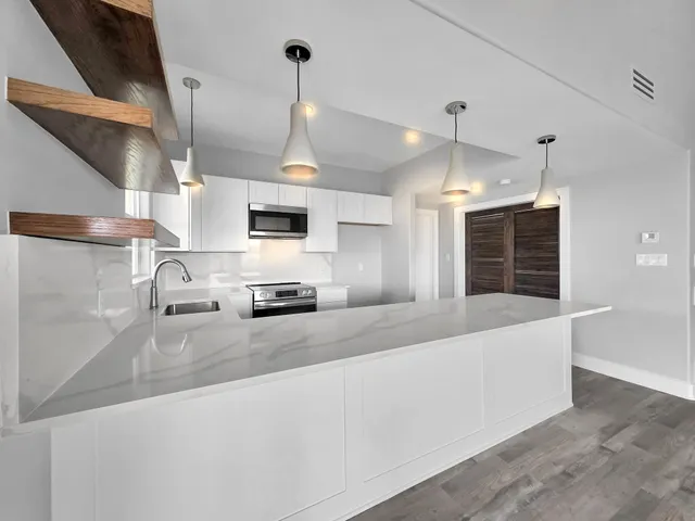 a large kitchen with stainless steel appliances kitchen island granite countertop a refrigerator a stove a sink and a wooden floors