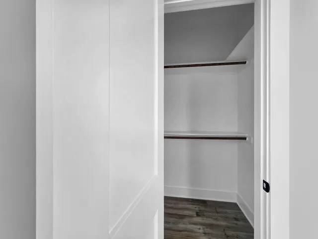 an empty room with wooden floor ceiling fan and windows