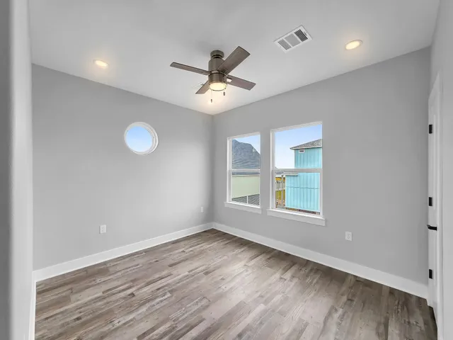 a view of an empty room with a window and wooden floor