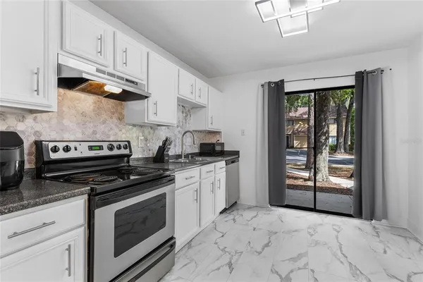 a kitchen with stainless steel appliances granite countertop a stove sink and cabinets
