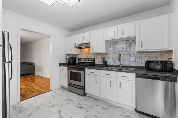 a kitchen with granite countertop a sink stainless steel appliances and cabinets