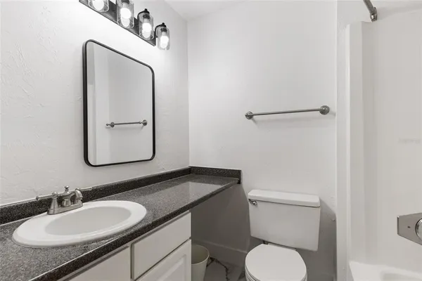a bathroom with a granite countertop toilet sink and mirror