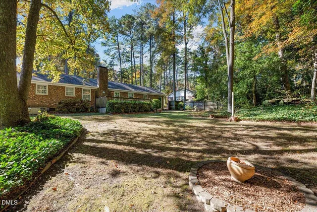 a backyard of a house with table and chairs plants and large trees