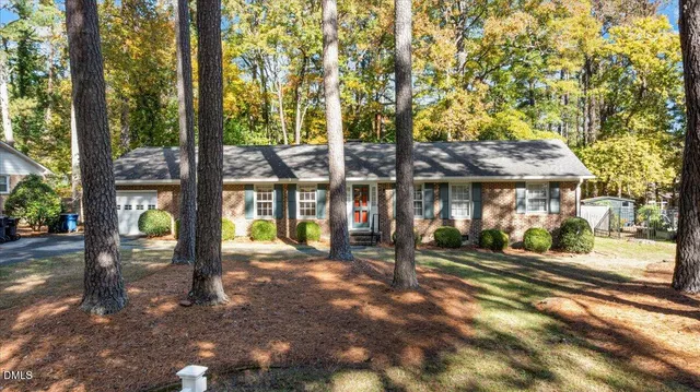 a front view of a building with a garden and trees
