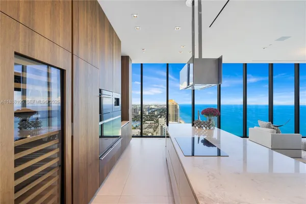 a large white kitchen with kitchen island a sink stainless steel appliances and cabinets