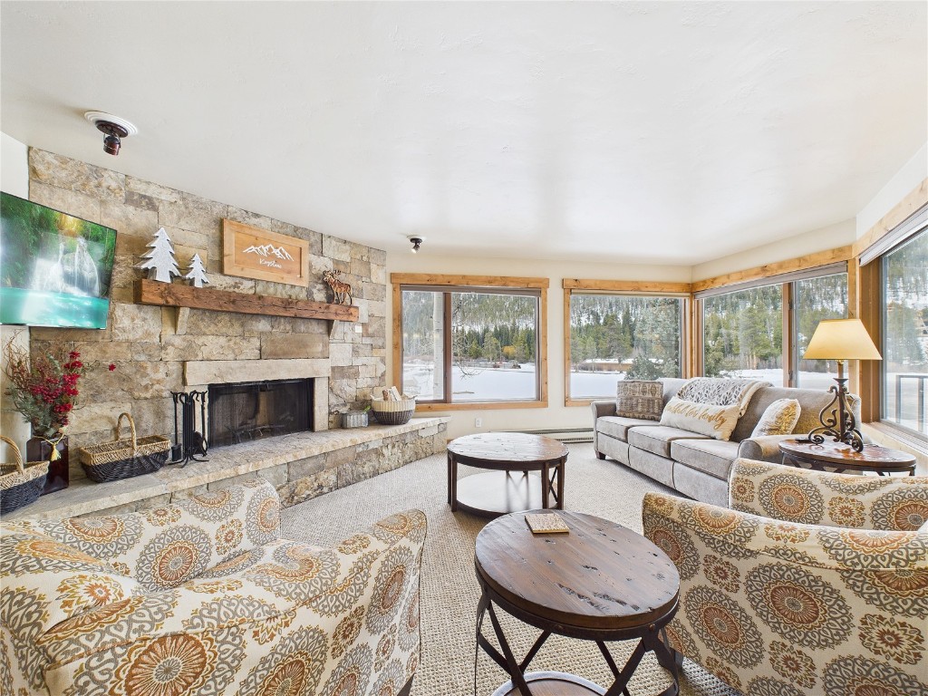 22280 Highway 6, Unit 1709 Keystone, CO 80435 - Photo 1 of 49 Bright living room with stone fireplace, large windows, and peaceful lake views