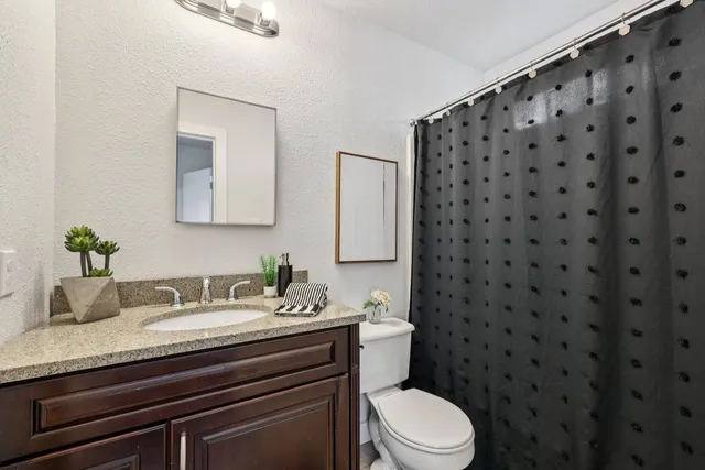 a bathroom with a granite countertop sink toilet and mirror