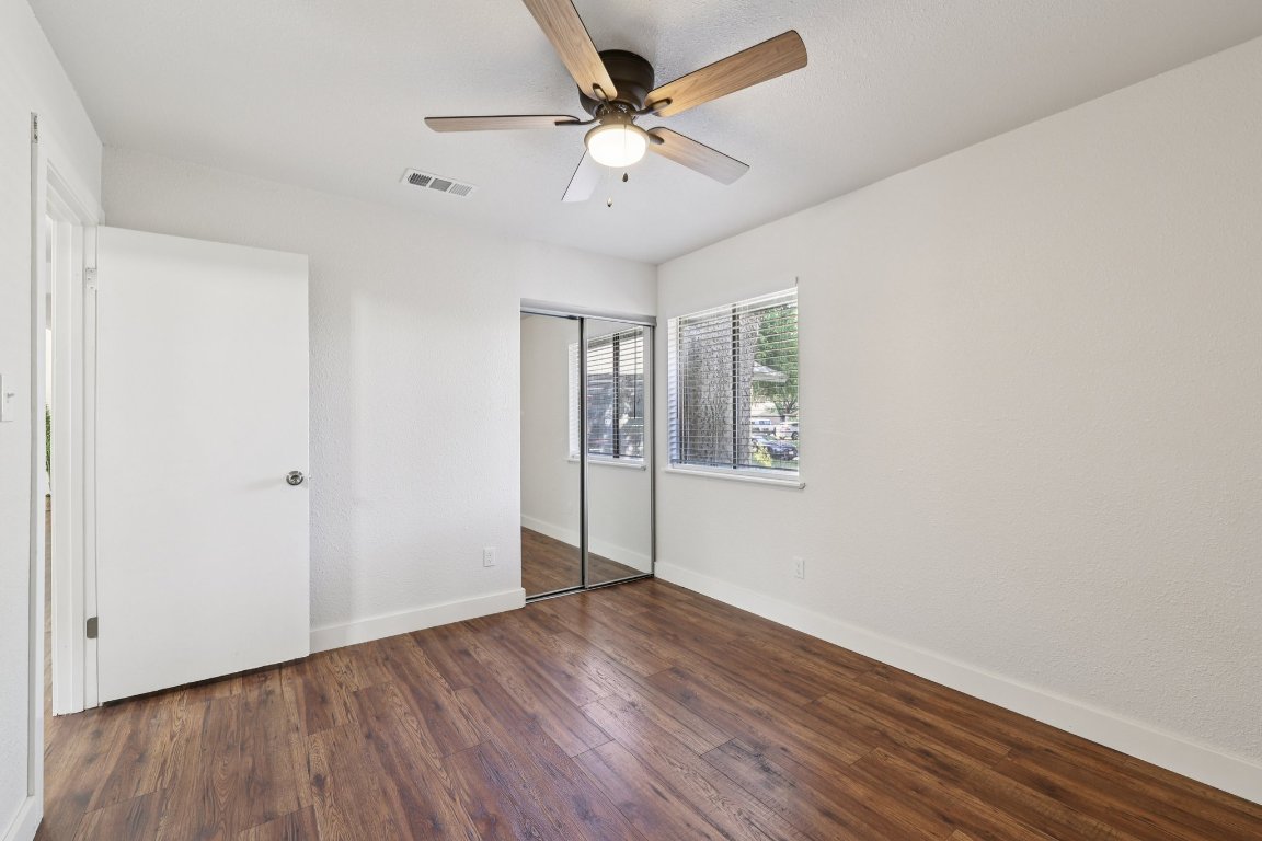 602 Old Stone Road Austin, TX 78745 - Photo 27 of 28 an empty room with wooden floor chandelier fan and windows
