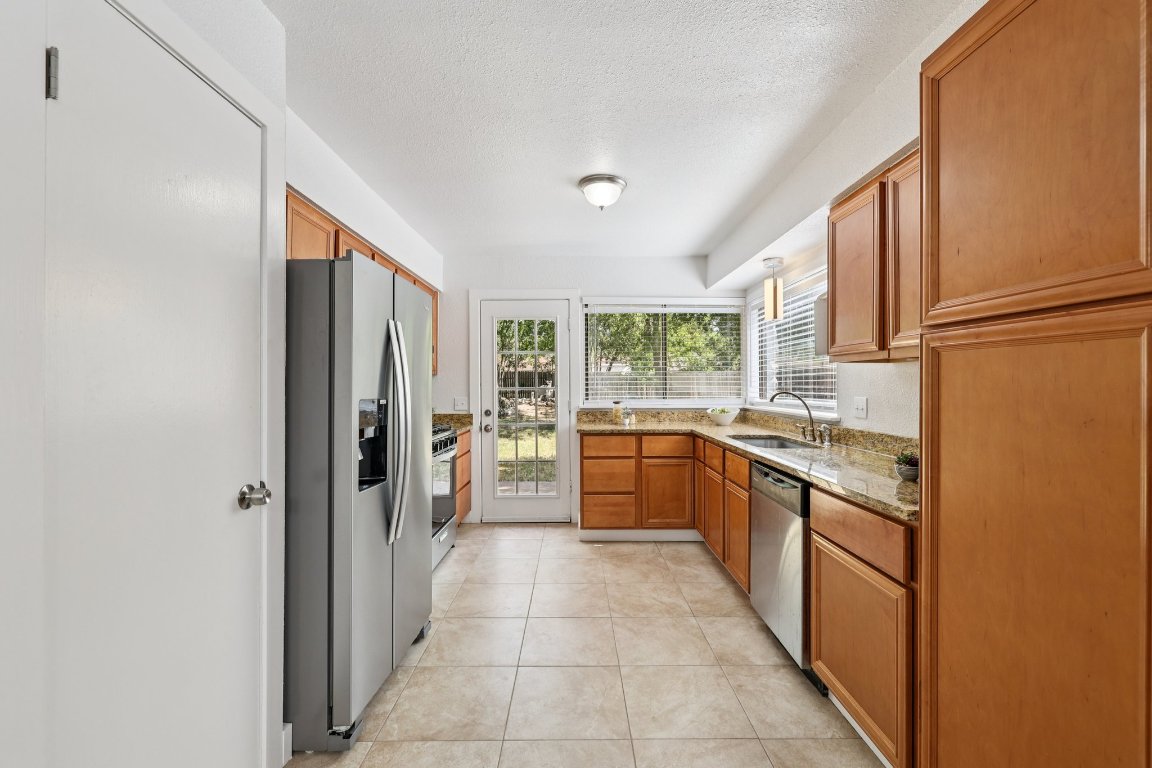 602 Old Stone Road Austin, TX 78745 - Photo 8 of 28 a large kitchen with a refrigerator a stove top oven and a dishwasher