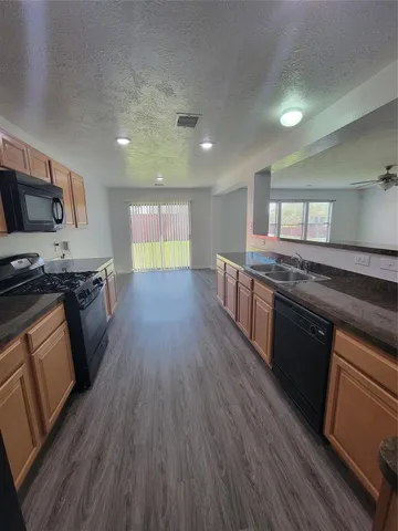 a kitchen with stainless steel appliances granite countertop wooden floors stove and sink