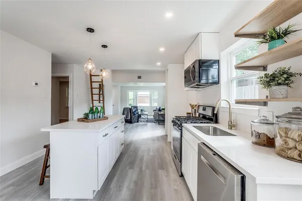 a large white kitchen with sink a stove and refrigerator