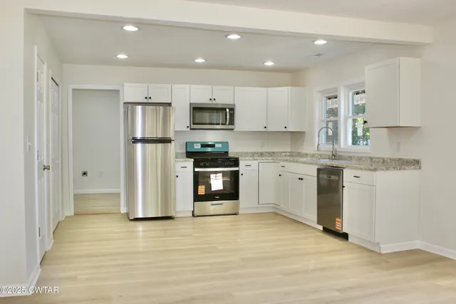 a kitchen with kitchen island granite countertop a stove a sink and a refrigerator