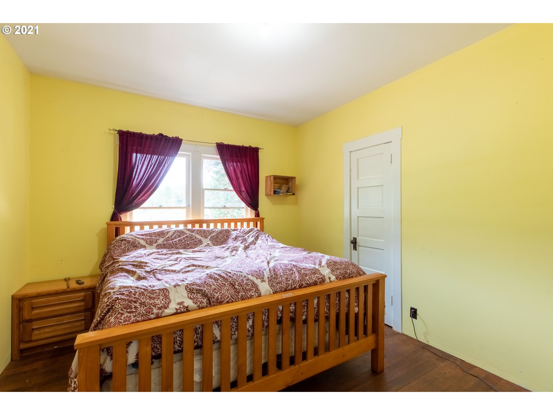 438 Soup Creek Road Reedsport, OR 97467 - Photo 23 of 30 a bedroom with a bed and wooden floor