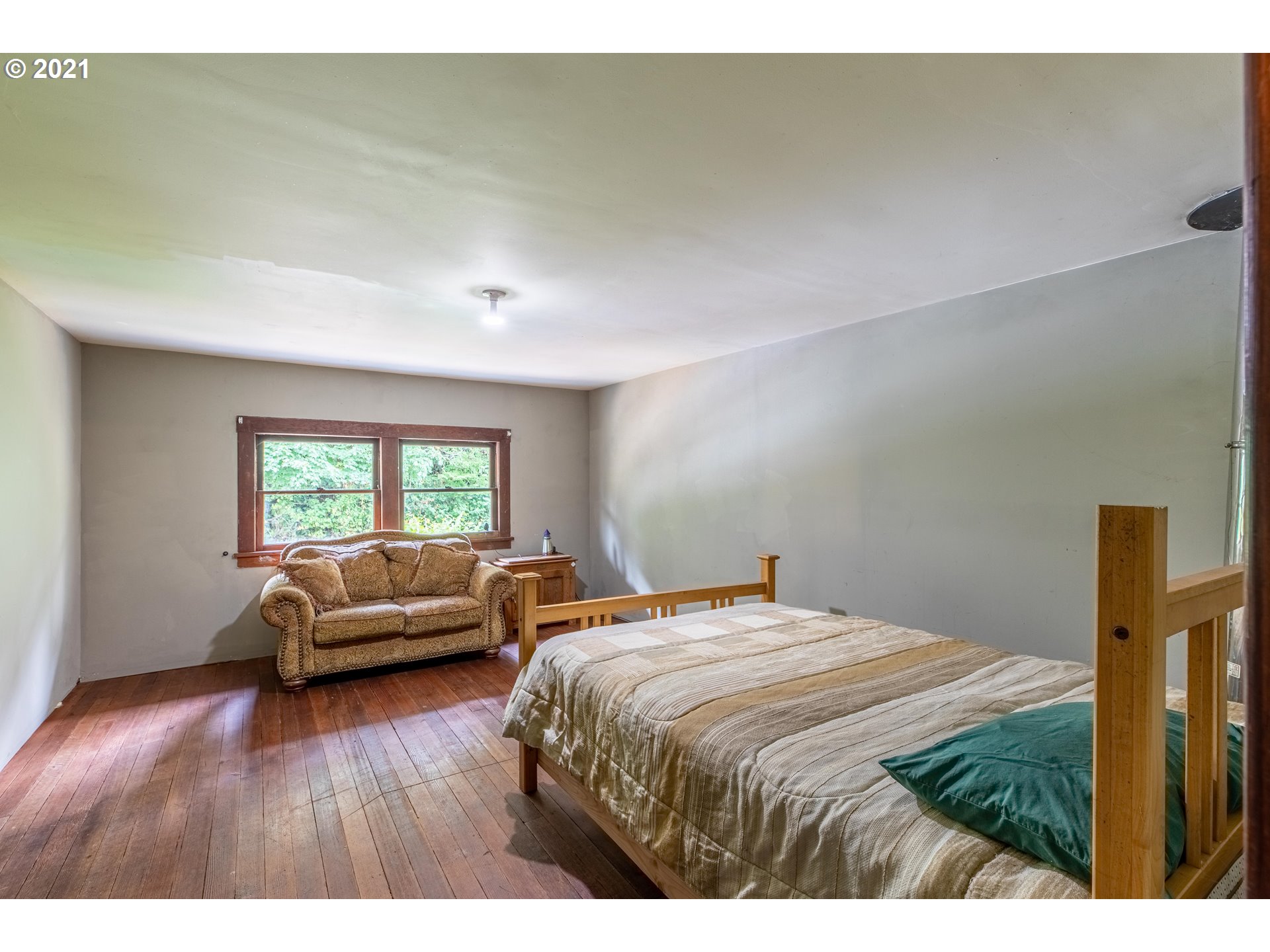 438 Soup Creek Road Reedsport, OR 97467 - Photo 27 of 30 a bedroom with a bed and a wooden floor