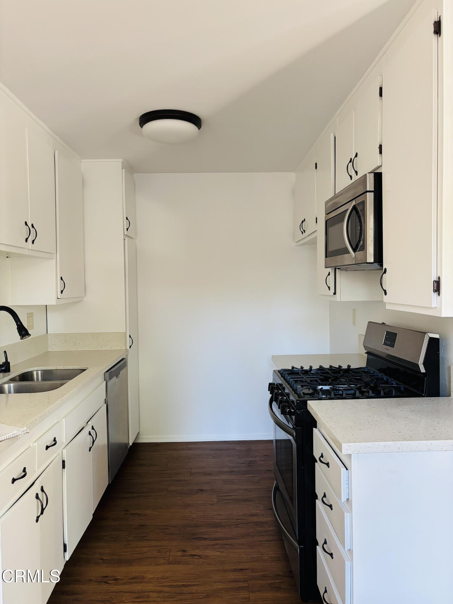 a kitchen with granite countertop a sink a stove and cabinets