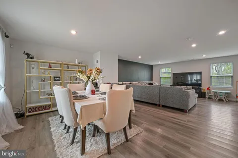 a living room with furniture and a dining table with wooden floor