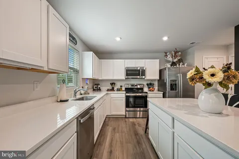 a kitchen with a sink dishwasher a stove top oven a refrigerator and cabinets with wooden floor