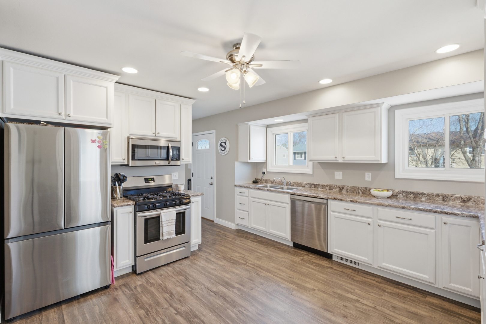 3443 3rd Street B East Moline, IL 61244 - Photo 4 of 23 a kitchen with stainless steel appliances a stove a sink a refrigerator white cabinets and wooden floor