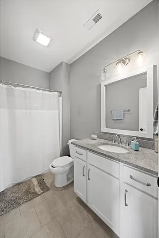 a bathroom with a granite countertop sink a toilet and a mirror