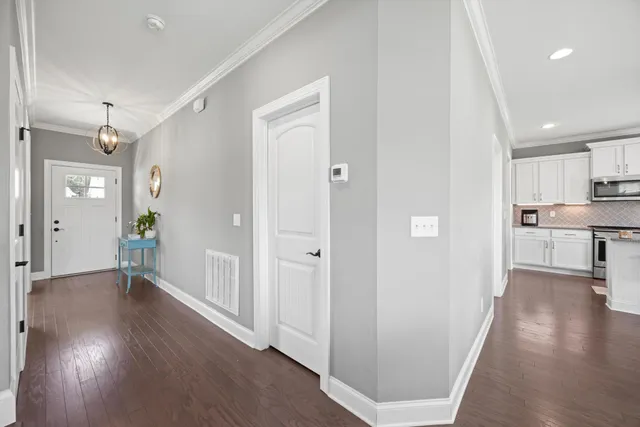a view of a hallway with wooden floor and a bathroom