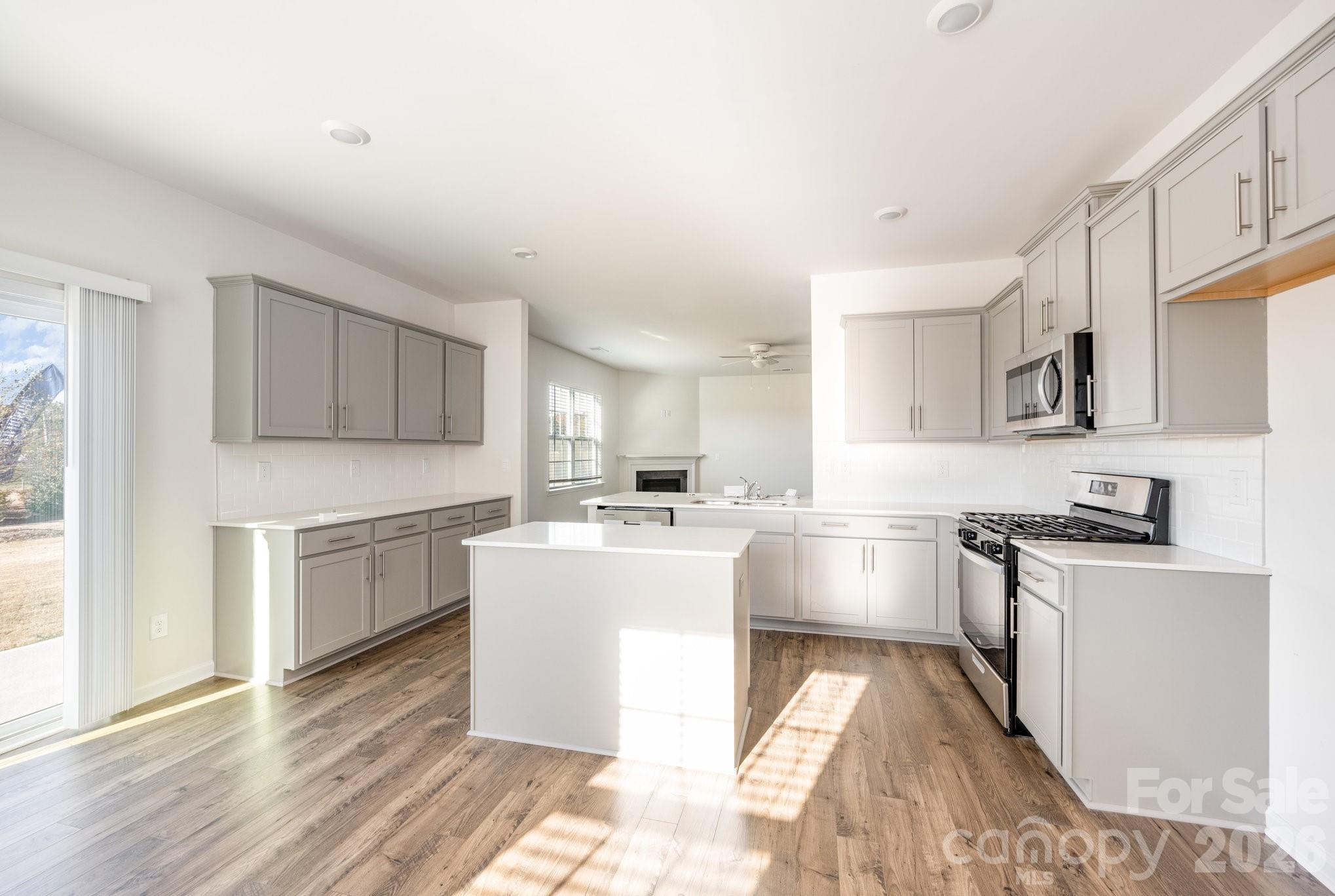 2116 Vanderlyn Street Monroe, NC 28112 - Photo 7 of 20 a kitchen with kitchen island a stove a sink dishwasher a refrigerator and white cabinets with wooden floor
