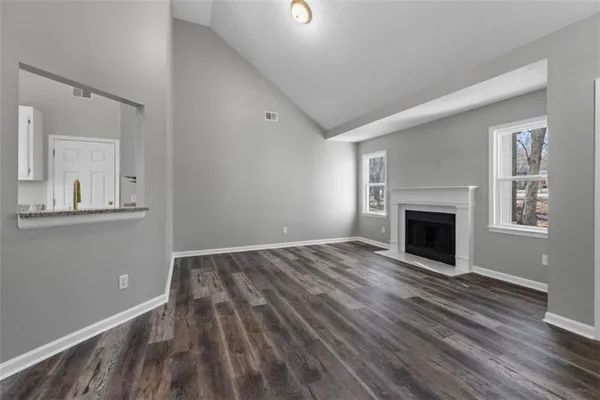 a view of empty room with wooden floor and fireplace