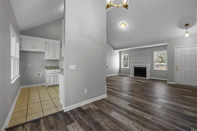 an empty room with wooden floor fireplace and windows